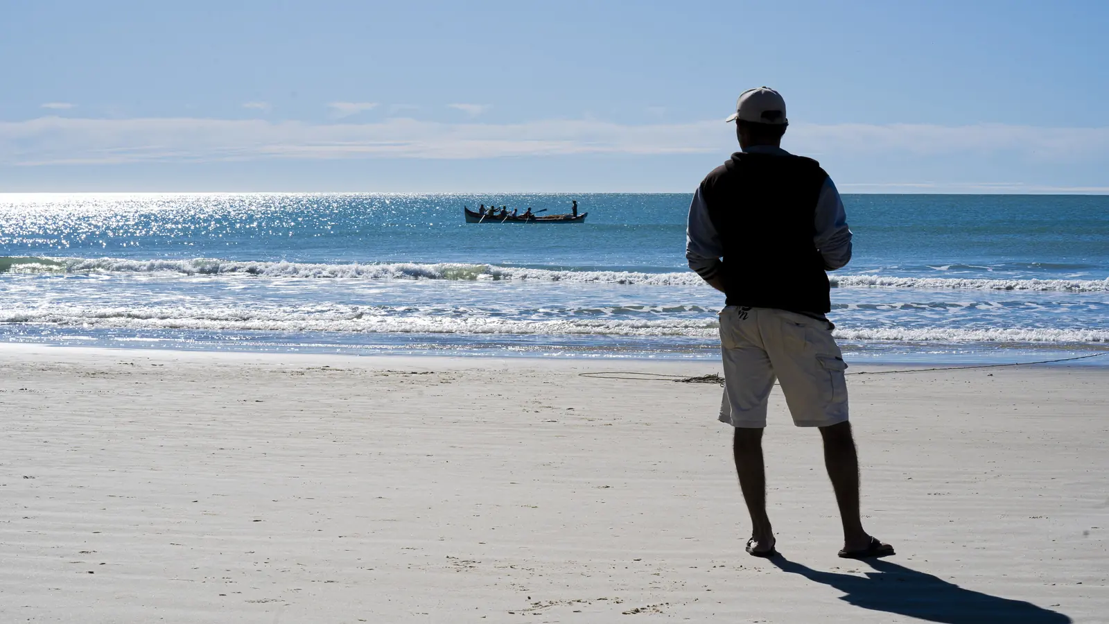 Pescador observa a canoa na Praia de Bombas